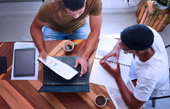 Mid Size Business Owners Drinking Coffee and Discussing Marketing Challenges at a Table Crunching Numbers