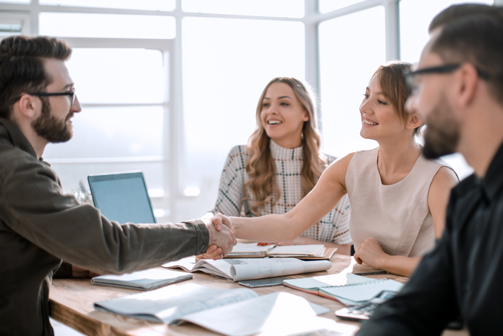 Small Business Sales Team Discussing Strategy with a Client Shaking Hands