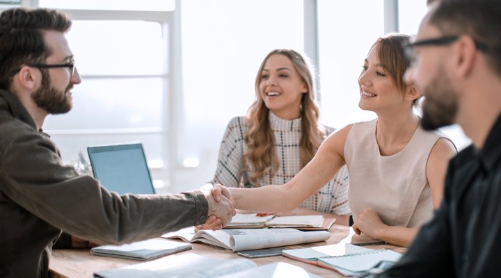 Small Business Sales Team Discussing Strategy with a Client Shaking Hands